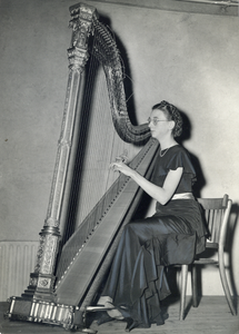 405065 Portret van mej. Y. van Heulen, harpiste van het Utrechts Stedelijk Orkest (U.S.O.) te Utrecht, met haar harp.